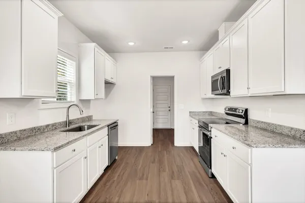 a kitchen with granite countertop a sink stainless steel appliances and white cabinets