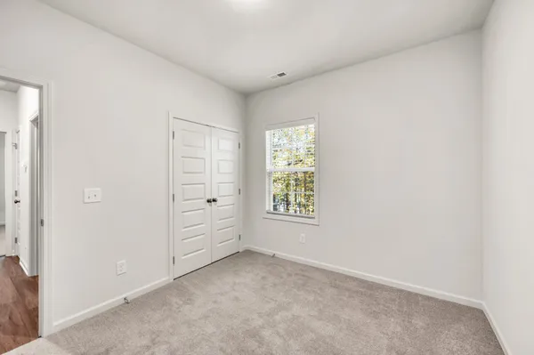 an empty room with closet and windows