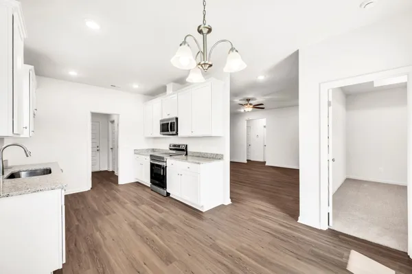 a kitchen with stainless steel appliances granite countertop wooden cabinets granite counter tops and a hard wood floors