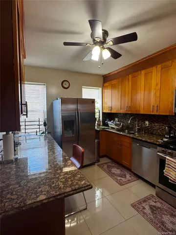 a kitchen with stainless steel appliances granite countertop a refrigerator a stove and a sink with wooden floor