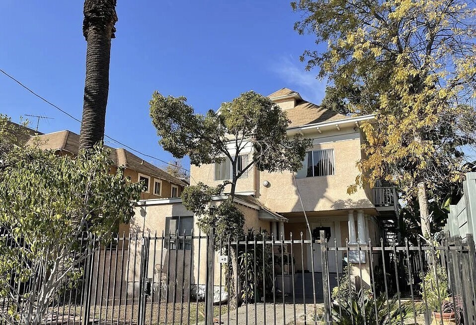 127 North Burlington Avenue, Unit C Los Angeles, CA 90026 - Photo 8 of 8 a view of a white house with large trees and wooden fence