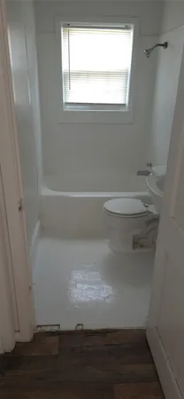 a view of empty room with wooden floor and a window
