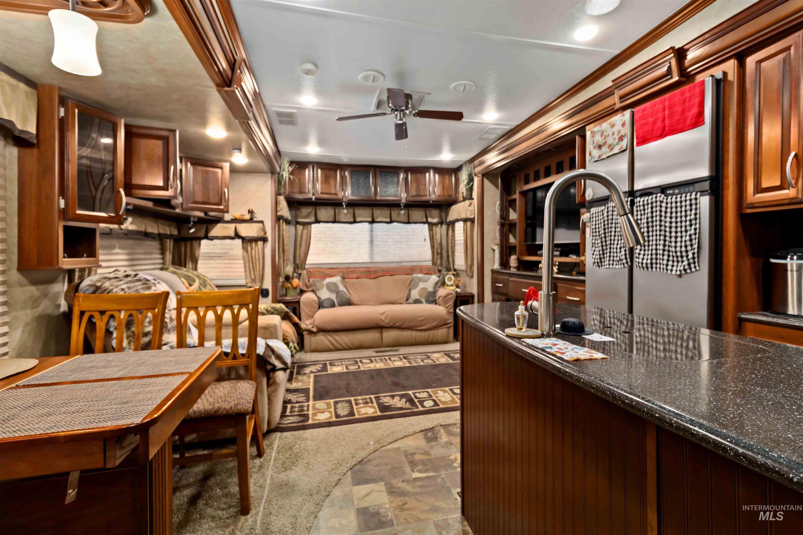 H05 North Sawyer Street Cascade, ID 83611 - Photo 21 of 40 Kitchen featuring dark stone finish flooring, dark stone counters, brown cabinets, ceiling fan, and freestanding refrigerator