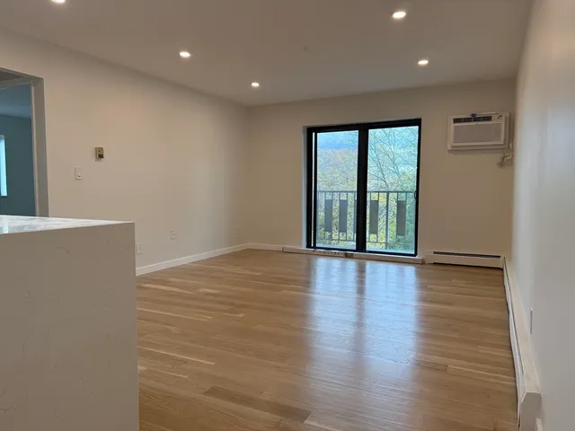 a view of an empty room with wooden floor and windows