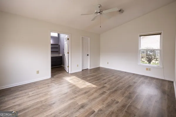 a view of an empty room with a window and wooden floor