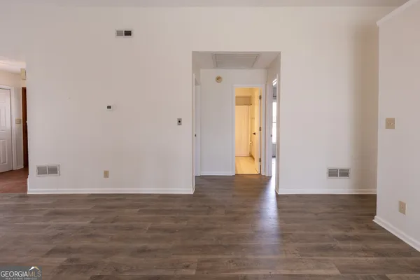 an empty room with wooden floor fireplace and windows