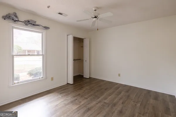 an empty room with wooden floor fan and windows
