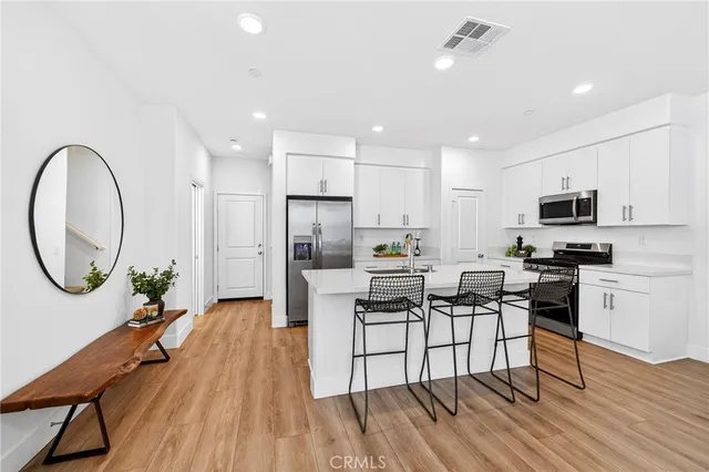a kitchen with stainless steel appliances a table chairs and a refrigerator