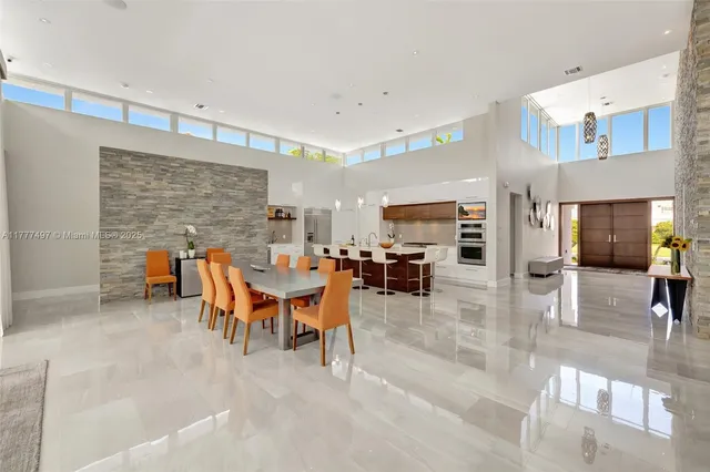 a dining room with stainless steel appliances kitchen island granite countertop a dining table chairs and a refrigerator