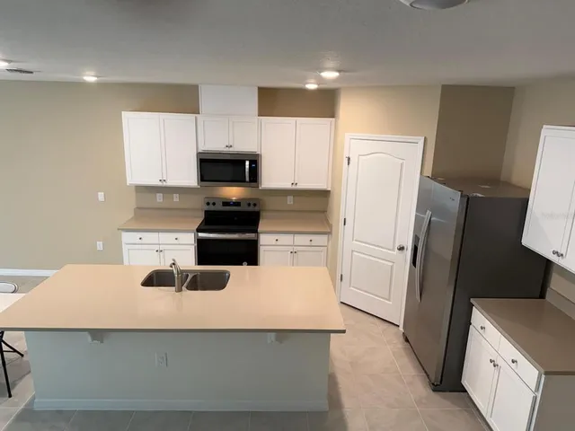 a kitchen with a refrigerator a stove top oven a sink and cabinets