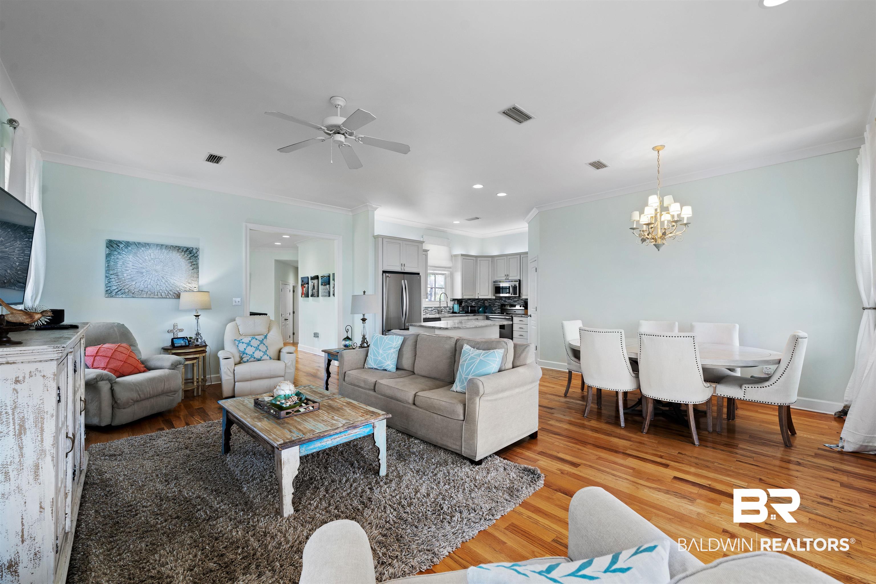 3434 Mariner Circle Orange Beach, AL 36561 - Photo 14 of 38 Living room with ceiling fan with notable chandelier, light hardwood / wood-style floors, crown molding, and plenty of room for enjoyment after a day at the beach.