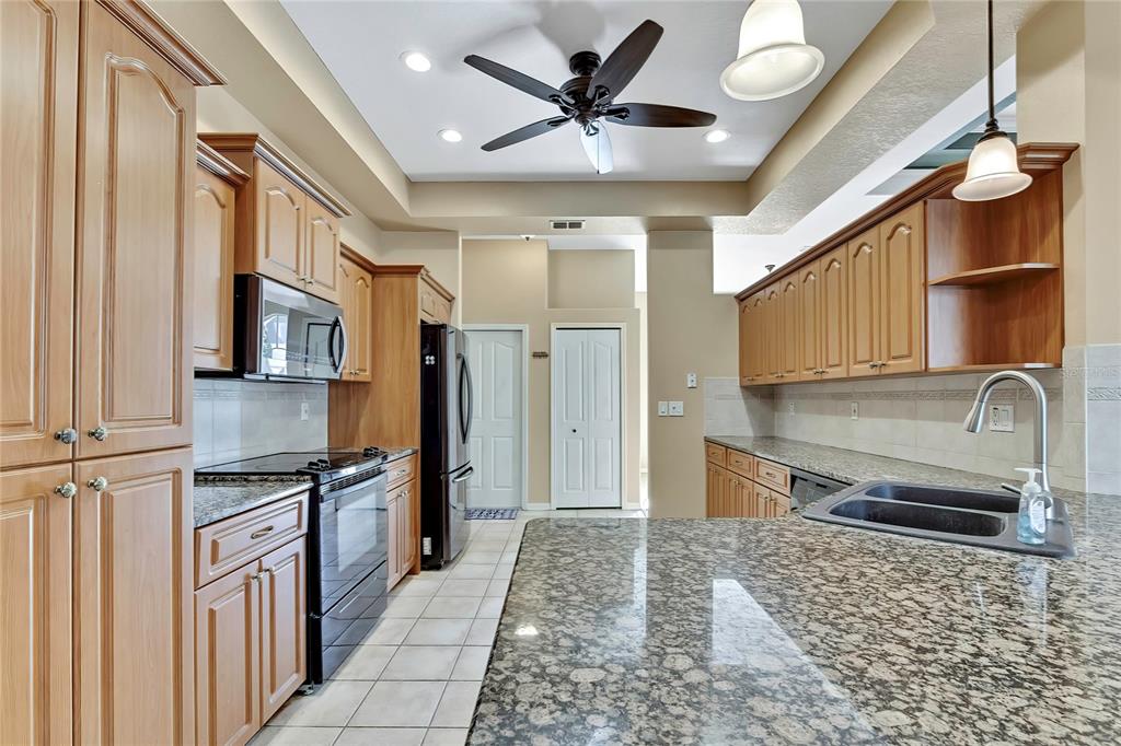 12403 Centennial Street Spring Hill, FL 34609 - Photo 18 of 62 a kitchen with stainless steel appliances granite countertop a refrigerator a stove and a sink with granite countertops