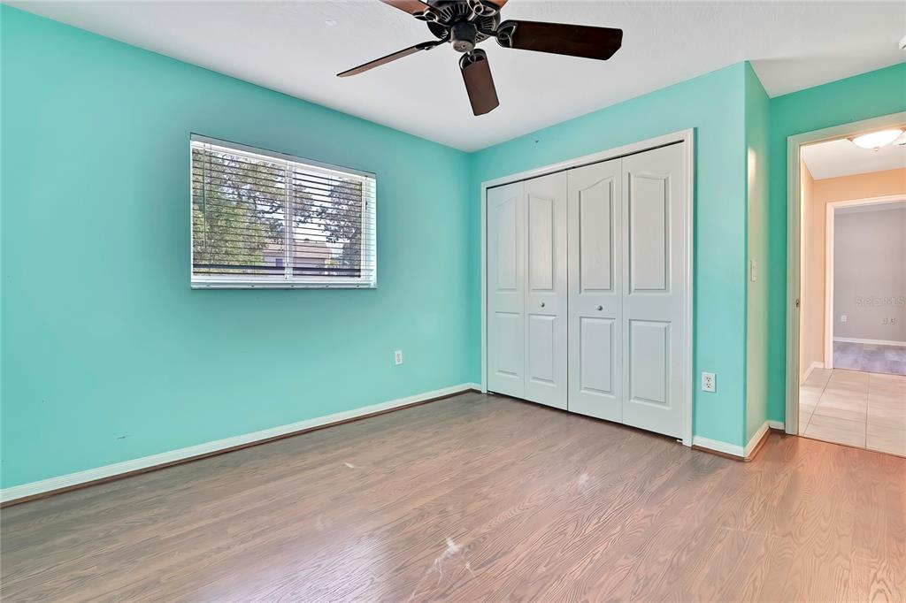 12403 Centennial Street Spring Hill, FL 34609 - Photo 39 of 62 an empty room with wooden floor ceiling fan and windows