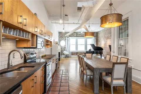 a kitchen with stainless steel appliances a table chairs sink and cabinets