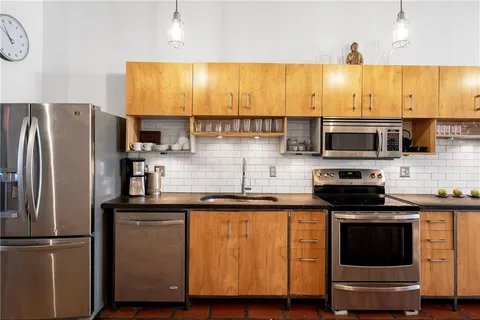 a kitchen with stainless steel appliances kitchen island granite countertop a table chairs and a wooden floors