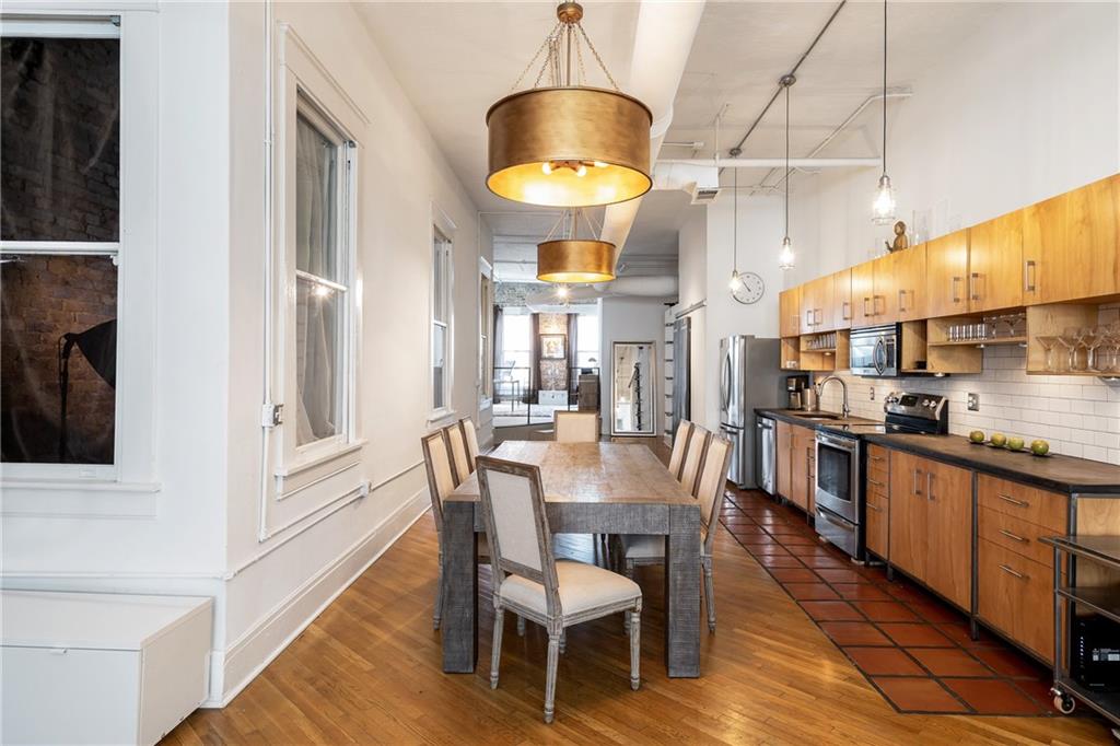 215 Mitchell Street Southwest, Unit 14 Atlanta, GA 30303 - Photo 20 of 37 a kitchen with stainless steel appliances kitchen island granite countertop a table chairs and a wooden floors