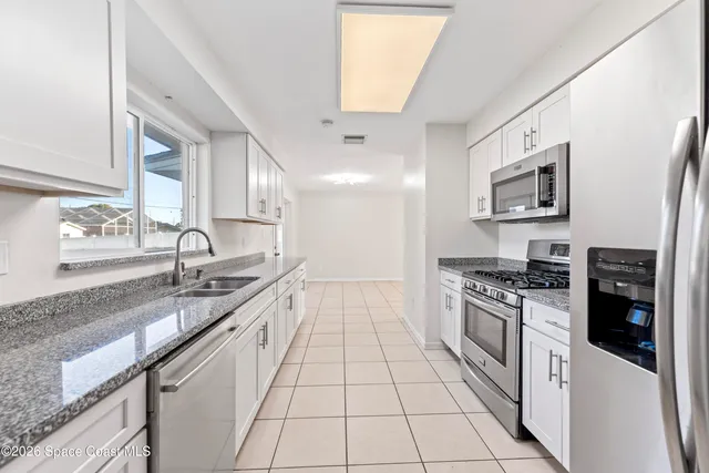 a large kitchen with stainless steel appliances granite countertop a sink stove and refrigerator