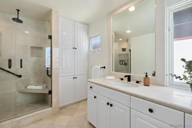 a bathroom with a mirror a vanity a sink and glass door shower