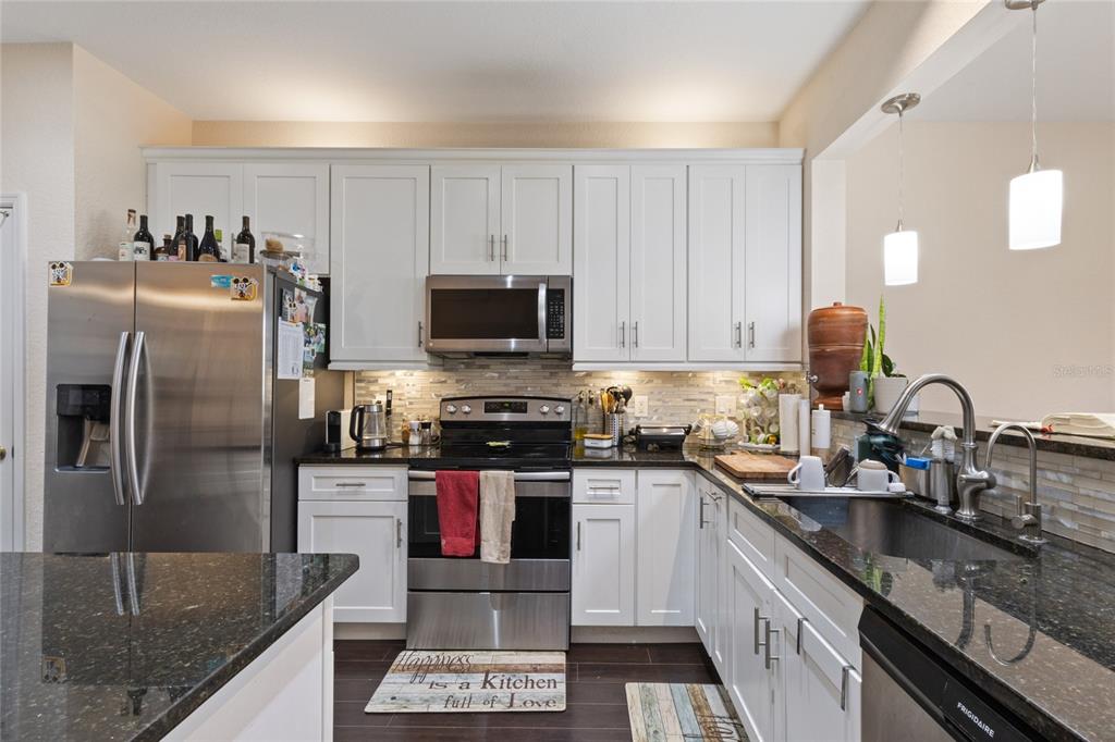 6435 Ranelagh Drive, Unit 104 Orlando, FL 32835 - Photo 14 of 36 a kitchen with stainless steel appliances granite countertop a sink a stove and a refrigerator