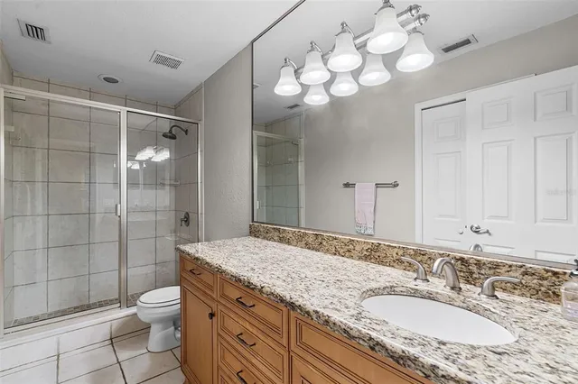 a bathroom with a granite countertop double vanity sink toilet and shower