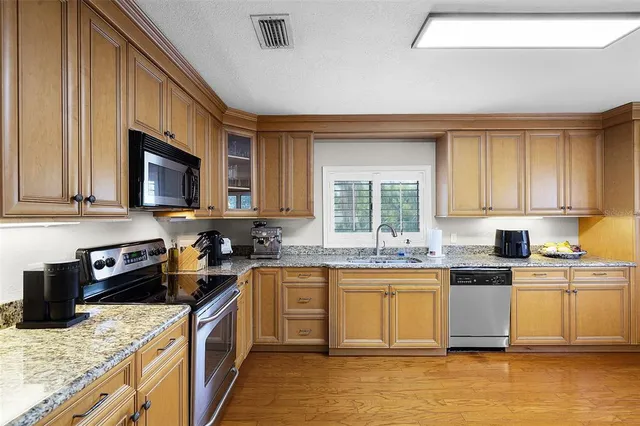 a kitchen with granite countertop a stove top oven sink and cabinets