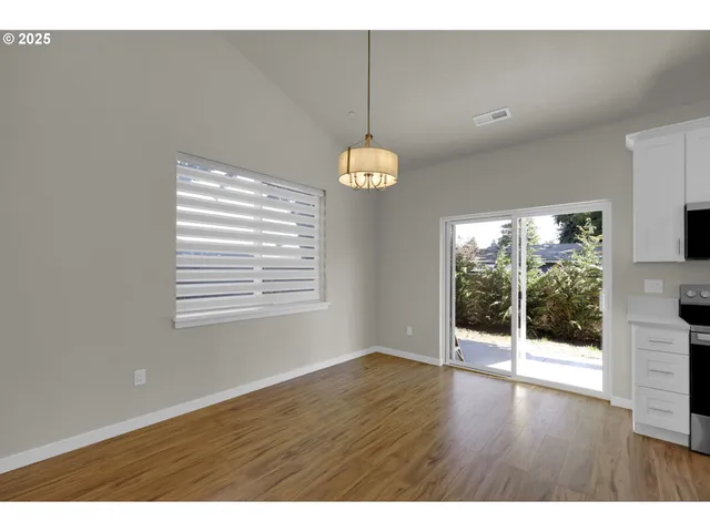 a open kitchen with stainless steel appliances kitchen island granite countertop a refrigerator a stove top oven a sink dishwasher and white cabinets with wooden floor