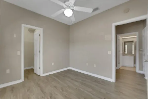 a view of an empty room with wooden floor and closet area