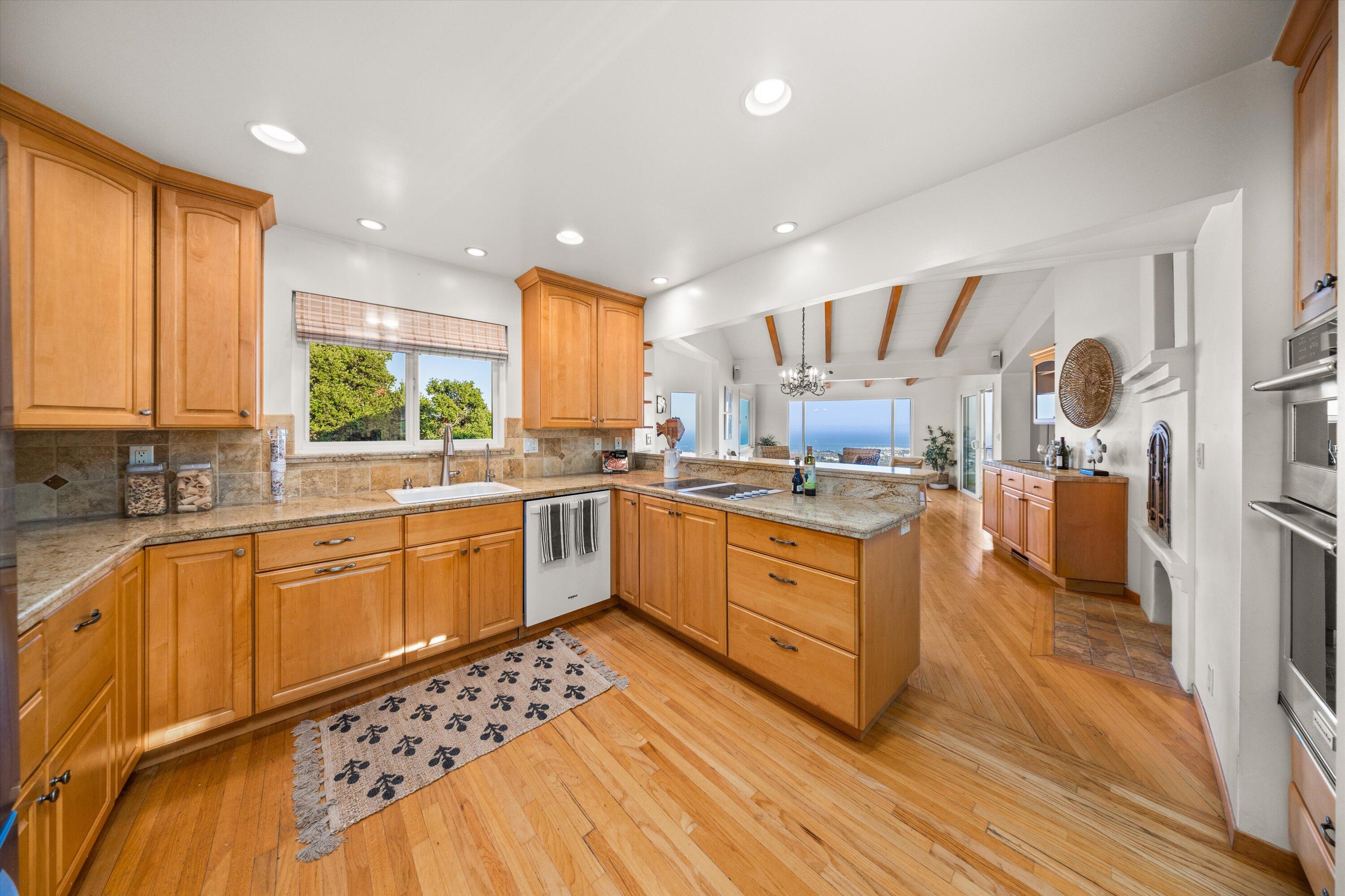 1227 Viscaino Road Santa Barbara, CA 93103 - Photo 12 of 25 a large kitchen with stainless steel appliances a large counter top a stove a sink dishwasher a refrigerator and cabinets with wooden floor