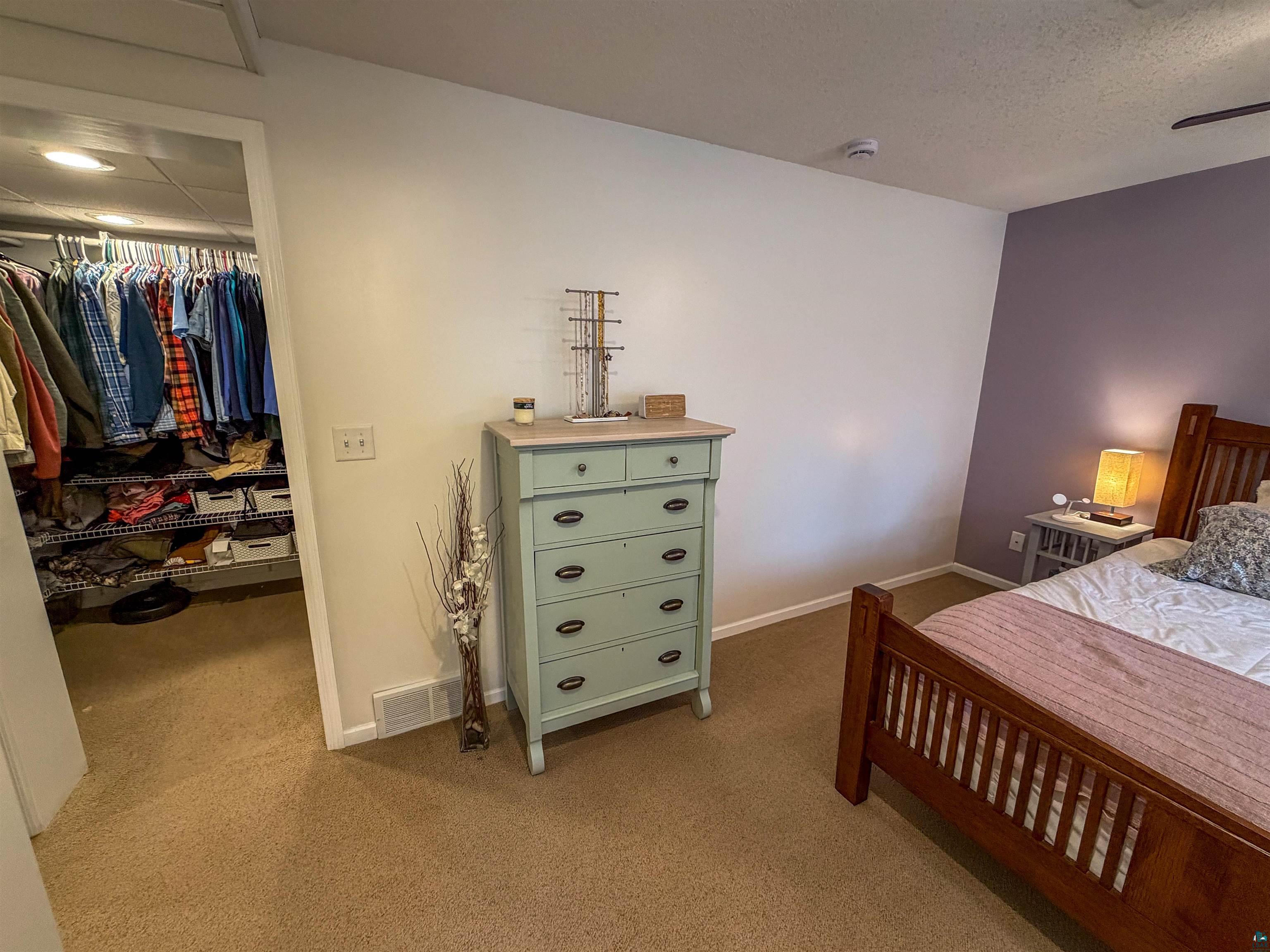 3704 Greysolon Road Duluth, MN 55804 - Photo 28 of 51 Carpeted bedroom featuring a dedicated closet entrance with built-in wire shelving and hanging rods, a ceiling-mounted fan, and a neutral color palette