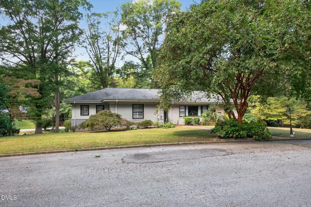 a view of a big house with a big yard and large trees
