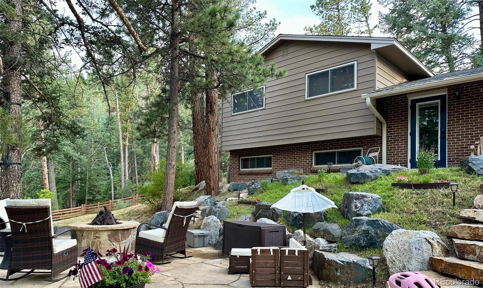 974 Wagon Trail Road Evergreen, CO 80439 - Photo 3 of 45 a view of a patio with table and chairs and a barbeque
