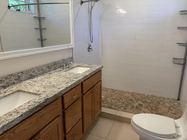 a bathroom with a granite countertop sink a toilet and a mirror