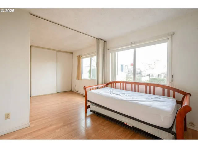 a bed sitting in a spacious bedroom next to a window