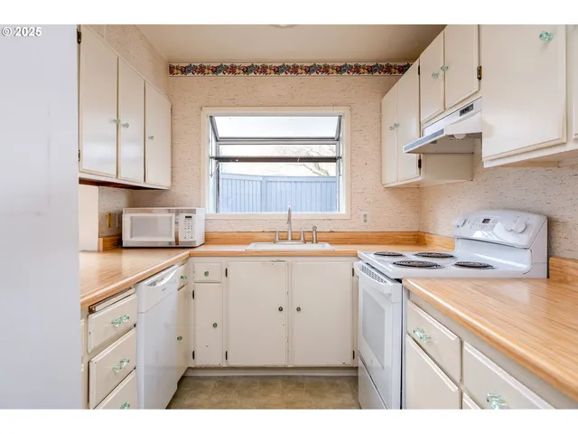 a kitchen with cabinets appliances a sink and a window