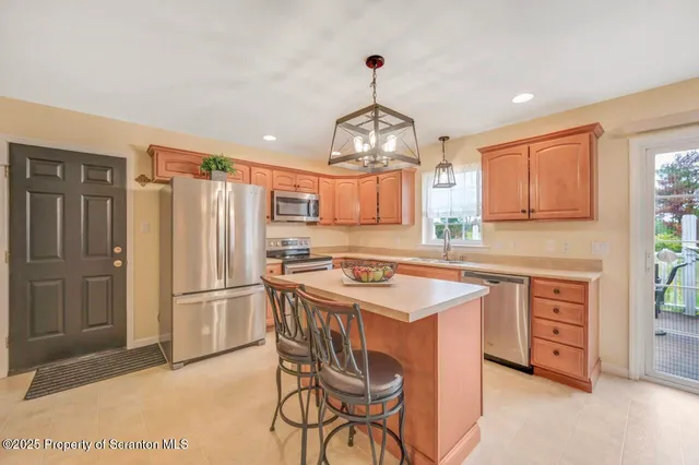a kitchen with stainless steel appliances a dining table chairs refrigerator and sink