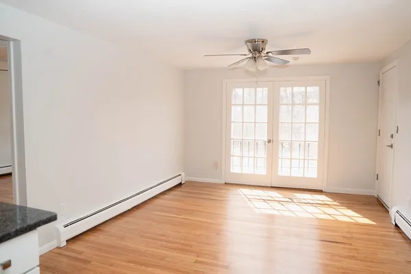 an empty room with wooden floor fan and windows