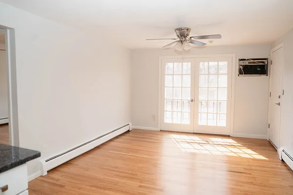 an empty room with wooden floor fan and windows