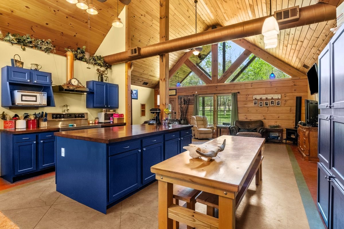 13631 Birdsong Road Holladay, TN 38341 - Photo 27 of 67 a kitchen with stainless steel appliances kitchen island granite countertop a table chairs in it and a wooden floor