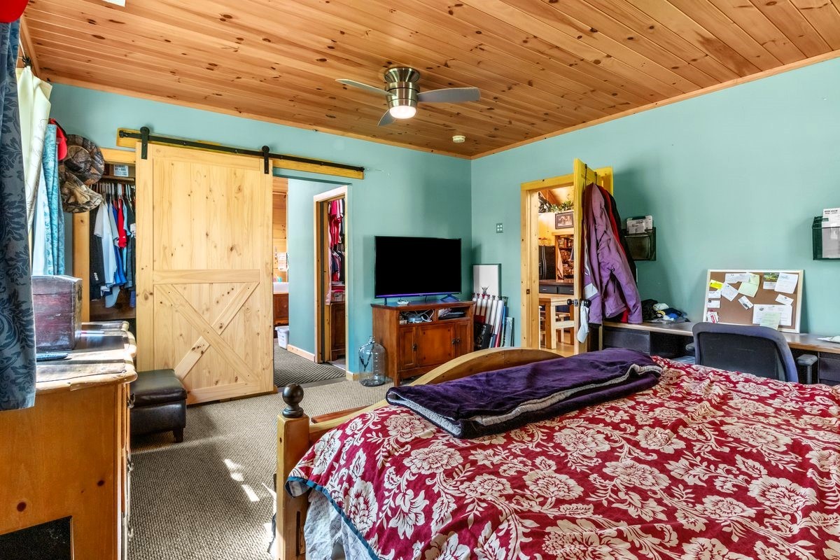 13631 Birdsong Road Holladay, TN 38341 - Photo 32 of 67 a bedroom with a bed a flat screen tv and a chandelier