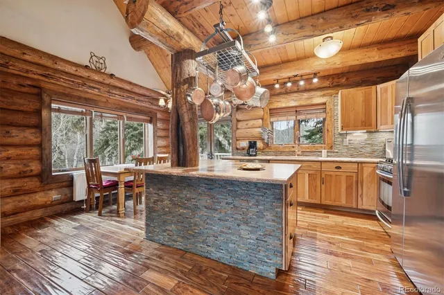 a living room with stainless steel appliances kitchen island granite countertop a sink and wooden floors