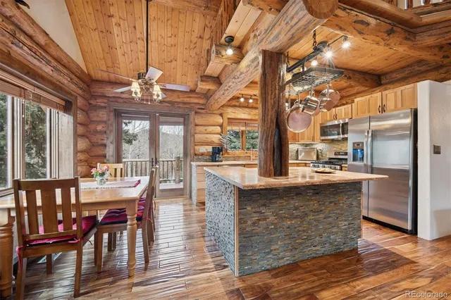 a dining hall with stainless steel appliances granite countertop a stove and cabinets with wooden floor