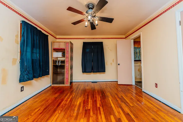 a view of room with wooden floor and a ceiling fan