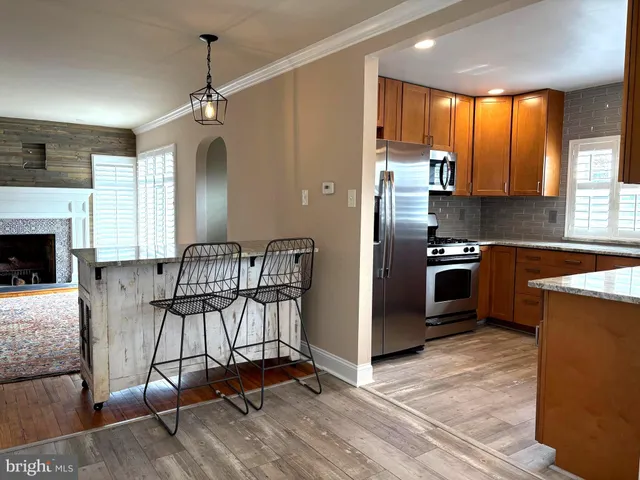 a kitchen with stainless steel appliances granite countertop a refrigerator a stove a sink dishwasher a dining table and chairs with wooden floor