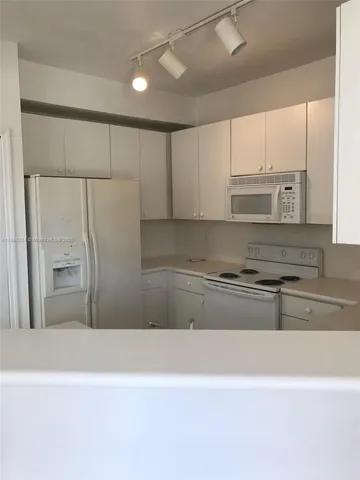 a kitchen with a refrigerator a stove top oven and white cabinets