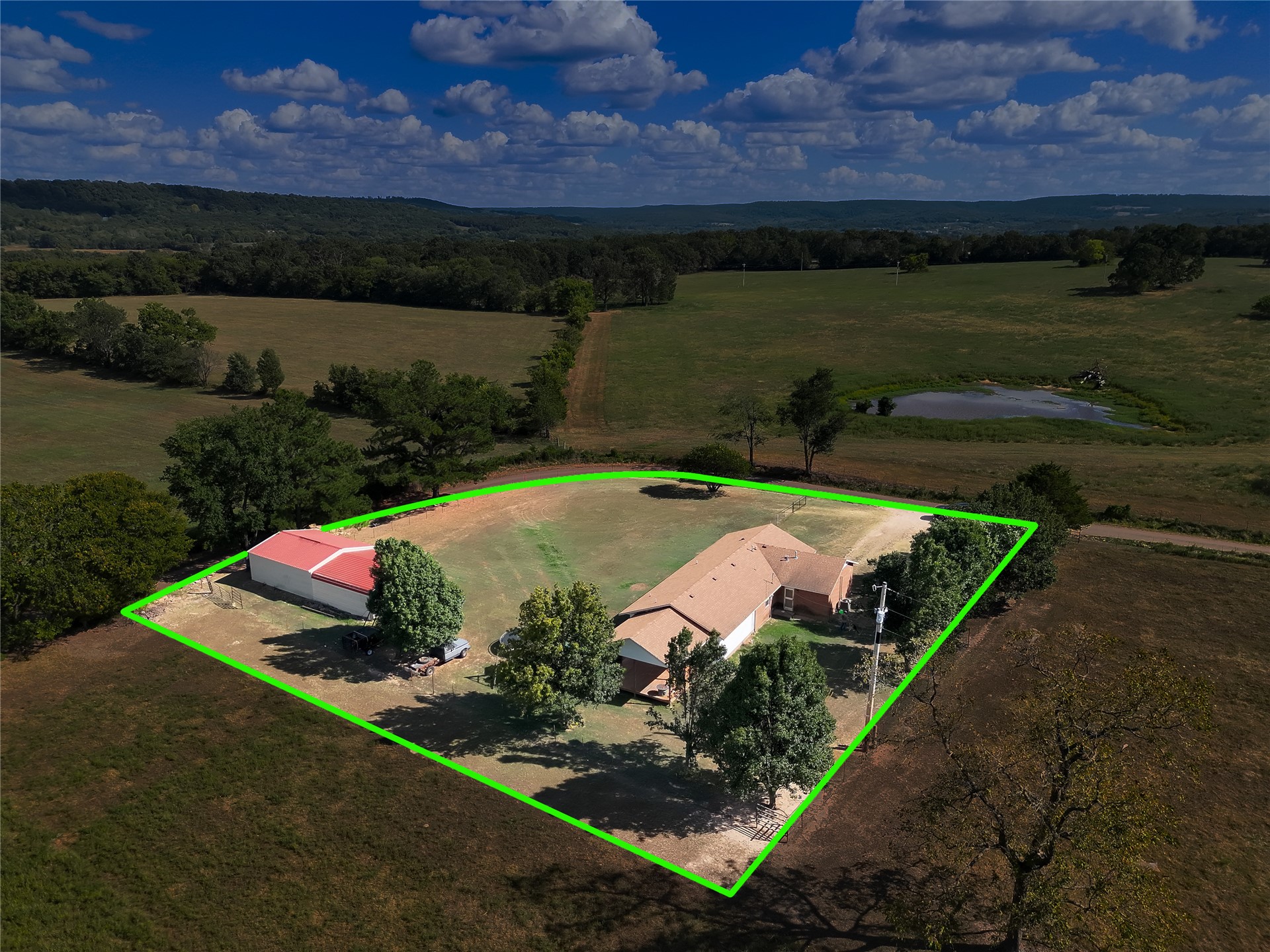 81232 South 4775 Road Stilwell, OK 74960 - Photo 16 of 50 Expansive property featuring a single-story residence, a large outbuilding with a red roof, mature trees, and open fields