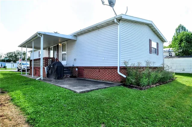 a view of a house with a yard plants and large tree