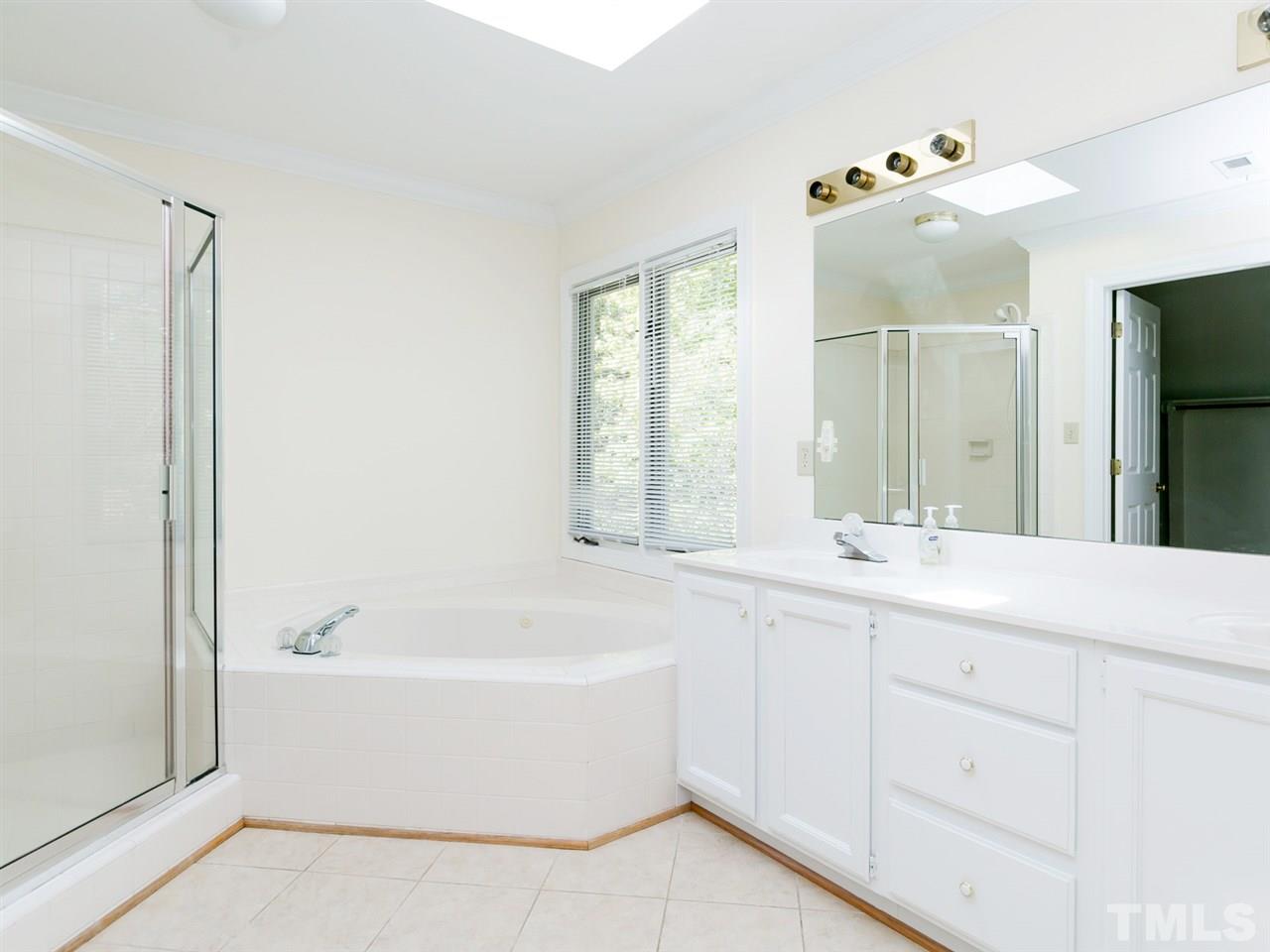 1312 Binley Place Raleigh, NC 27615 - Photo 11 of 22 a bathroom with a bathtub a mirror a double vanity sinks and vanity