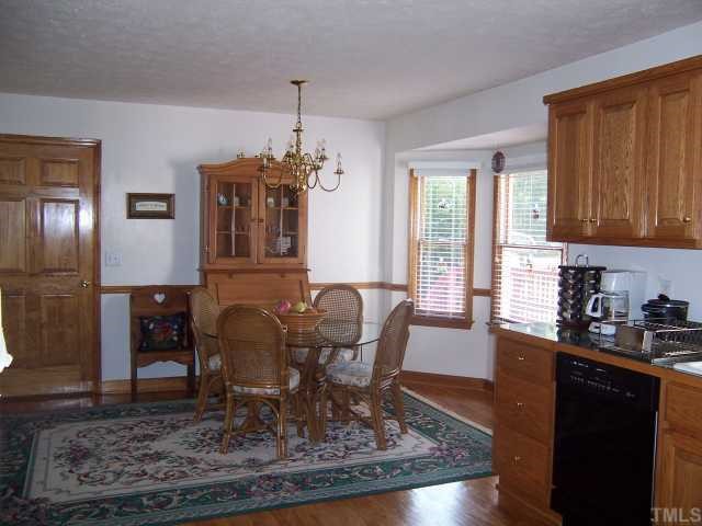 2431 Flat River Church Road Roxboro, NC 27574 - Photo 6 of 12 a dining room with wooden floor a chandelier a wooden table and chairs