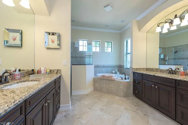 a bathroom with a granite countertop double vanity sink mirror and bathtub
