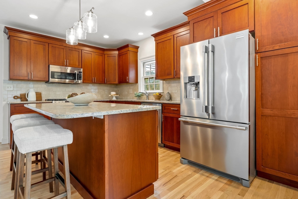 108 Warren Street Arlington, MA 02474 - Photo 13 of 42 a kitchen with stainless steel appliances granite countertop a refrigerator a sink dishwasher a stove top oven a kitchen island and chairs with wooden floor